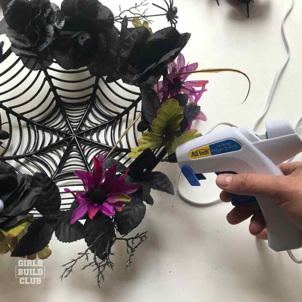 Start gluing the flowers on your spooky diy halloween wreath.  Super easy and cheap halloween decor craft project from the dollar store.  This would make a great halloween party or halloween wedding decoration.